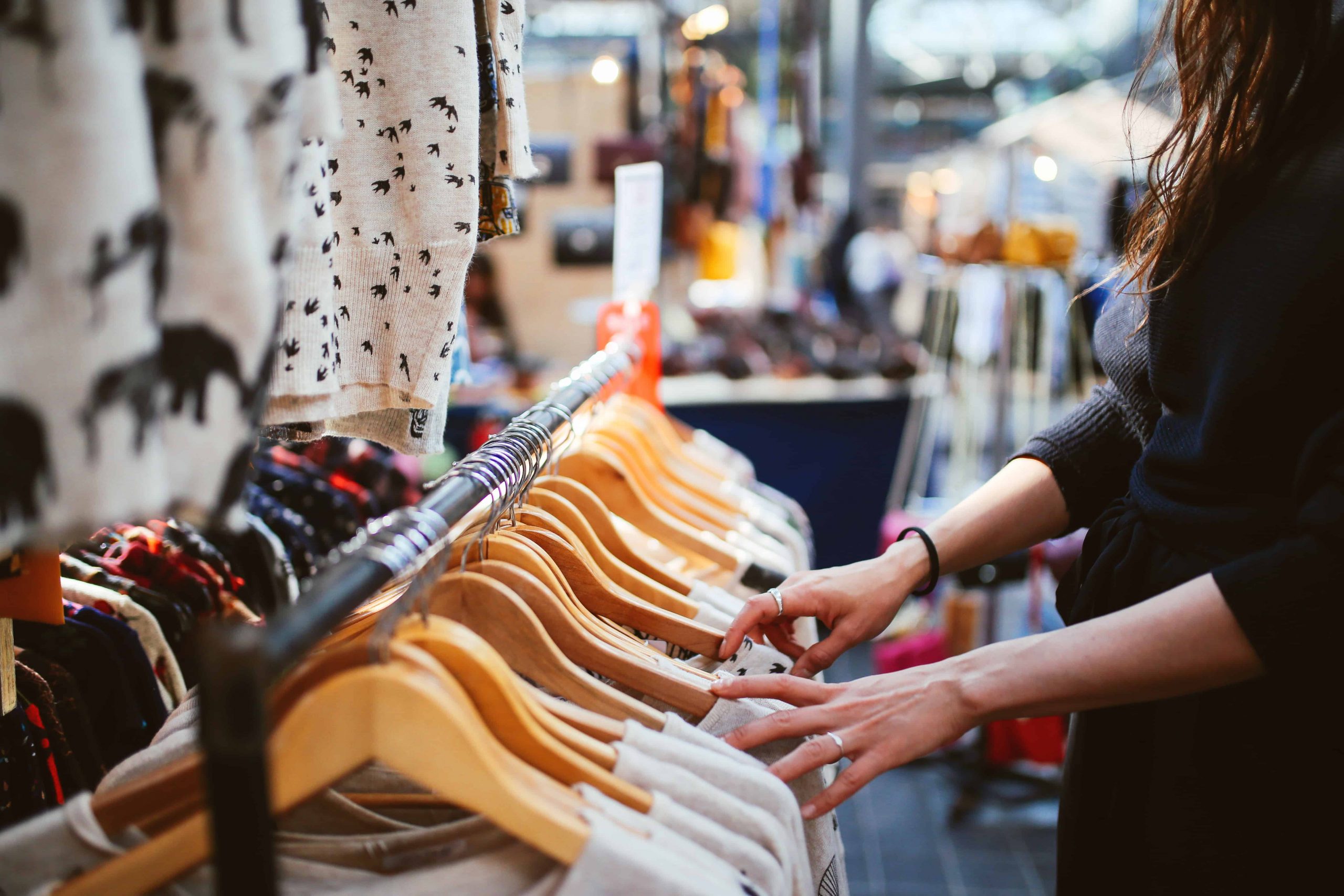 Goodwill AZ | Someone looking through racks of white shirts on hangers