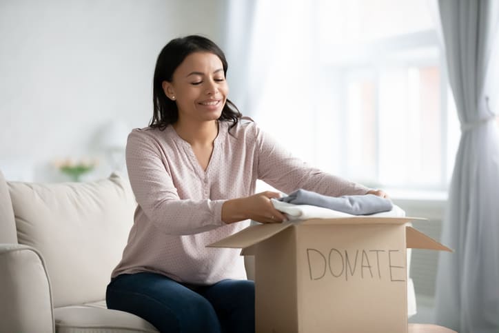 Goodwill AZ | woman putting cloths in a box labeled donate clothes