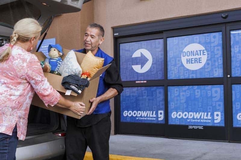 Goodwill AZ | Women passing a box of donations to a man