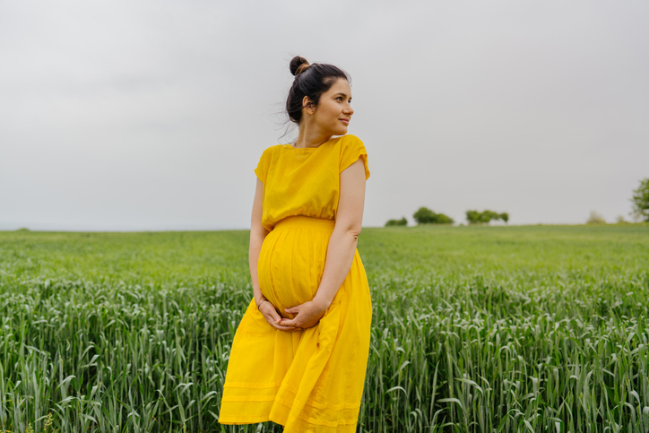 Goodwill AZ | Photo of a pregnant woman standing alone on a grass field