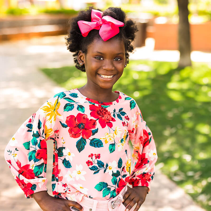 Goodwill AZ | Girl in a pink floral shirt smiling outside