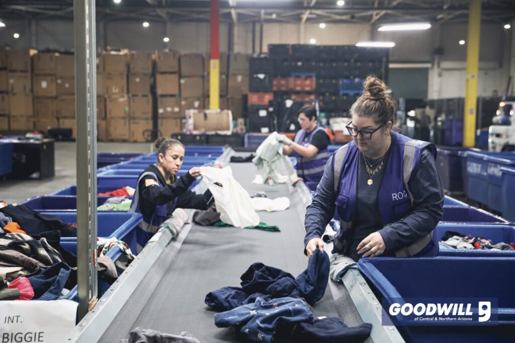 People working in a Goodwill warehouse sorting clothes